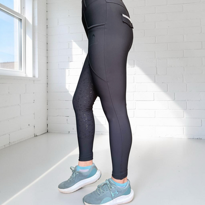 Wild Bay Equestrian black high-waisted riding leggings with silicone knee grip and side pockets, side profile view.